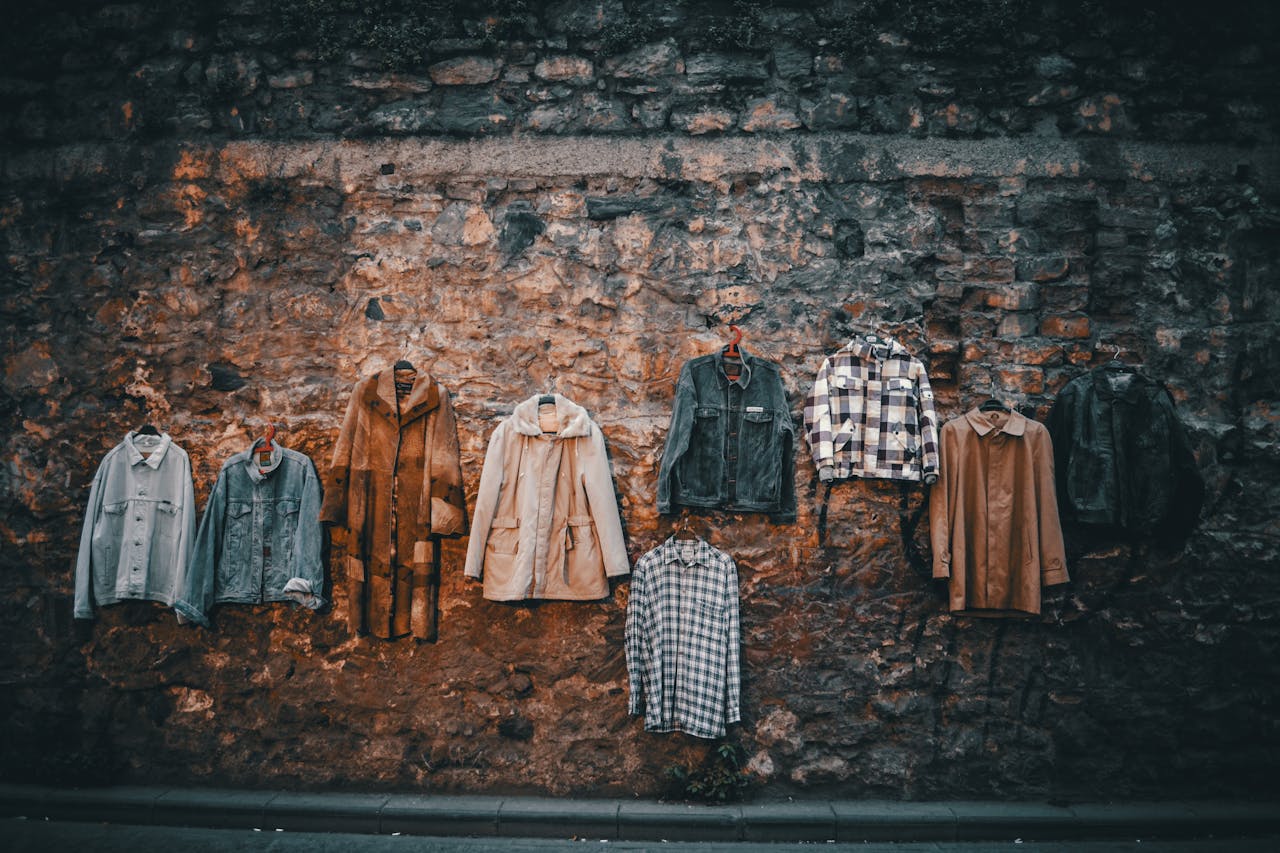 Different shirts and jackets placed for sale on aged stone wall of urban street